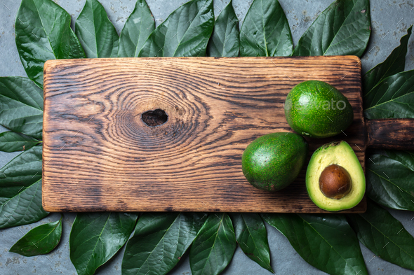food background with fresh avocado, avocado tree leaves and wooden cutting  board. Harvest concept Stock Photo by lblinova