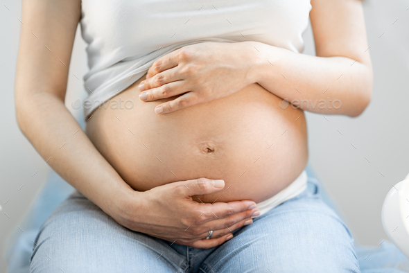 Pregnant woman hugging her belly - Stock Photo - Images