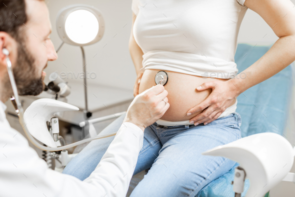 Doctor listening to a pregnant woman's belly - Stock Photo - Images