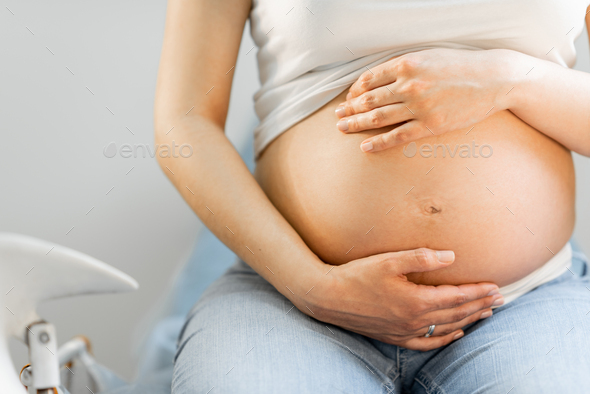 Pregnant woman hugging her belly - Stock Photo - Images