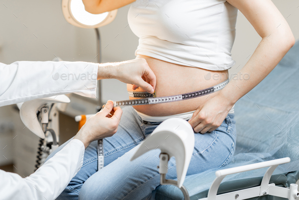 Measuring pregnant woman's belly with a tape - Stock Photo - Images