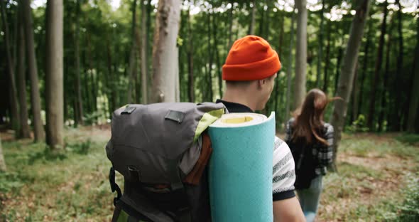 Couple of Backpacked Tourists Walking in Forest