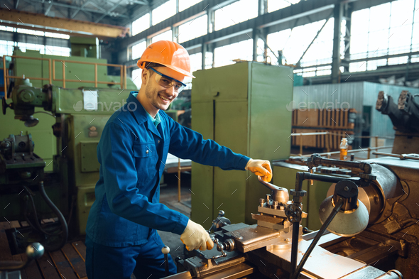 Male worker checks turning lathe on plant - Stock Photo - Images