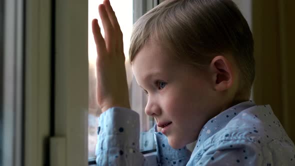 Sad Little Boy Sitting At Window And Looking At Snow