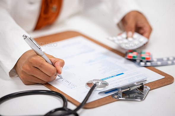 Doctor writing and checking medical prescription - Stock Photo - Images