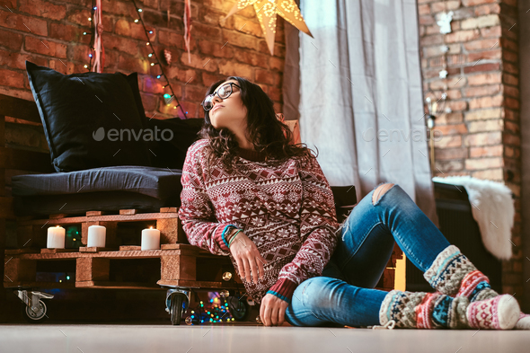 Cheerful beautiful girl sitting on a couch with gift boxes in a decorated room with loft interior. - Stock Photo - Images