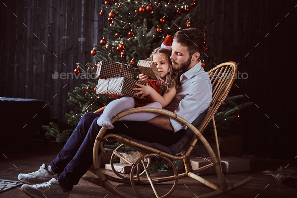 Dad and daughter holding gift boxes while sitting together on a rocking chair