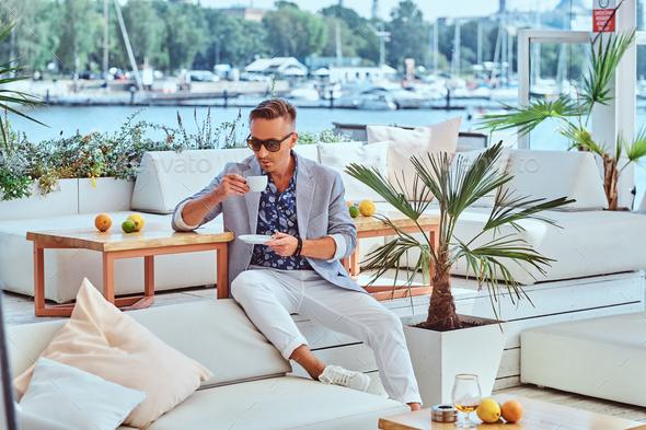 Successful man in modern elegant clothes at outdoor cafe against the background of city wharf. - Stock Photo - Images