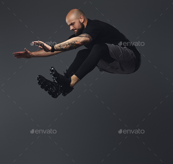 Handsome bearded athlete in sportswear jumping in a studio.