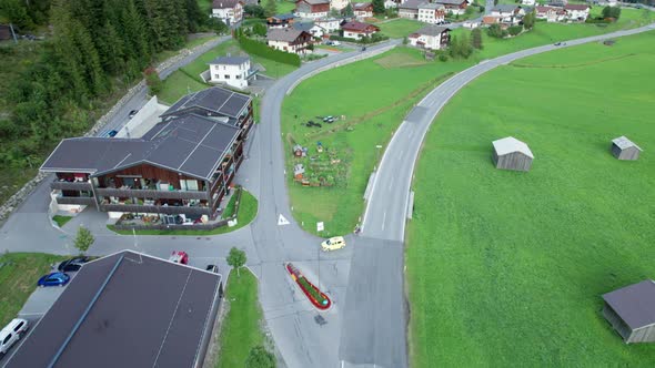 Road in Austrian Alp Valley Between Green Fields and Wooden Houses Aerial View alt