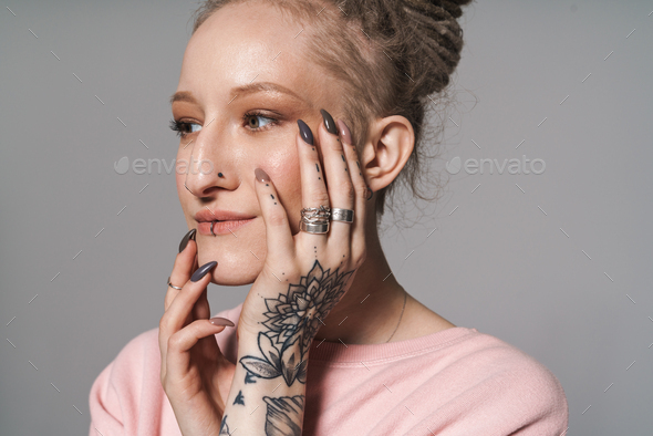 Image of extraordinary girl with tattoo and piercing touching her face