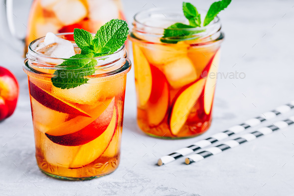 Homemade peach iced tea or lemonade with fresh mint and ice cubes in glass jar