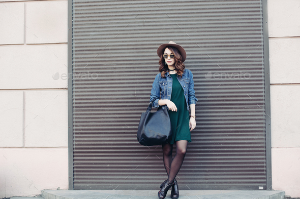 Stylish brunette in sunglasses and hat posing at street - Stock Photo - Images