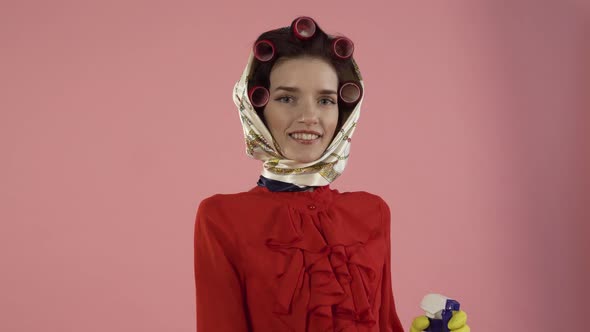 A Woman with Curlers on Her Hair Washes the Invisible Glass with Spray and a Rag