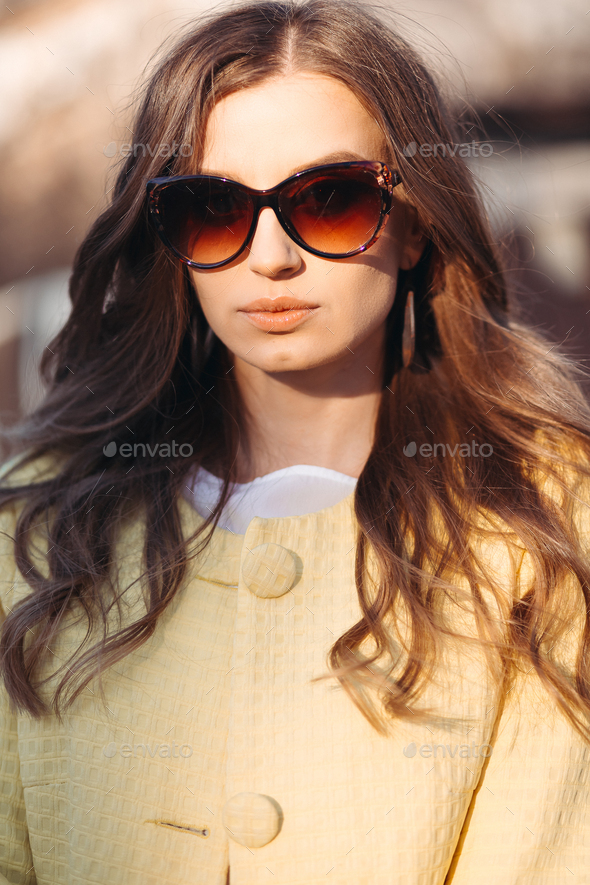 Brunette woman in sunglasses and yellow coat - Stock Photo - Images