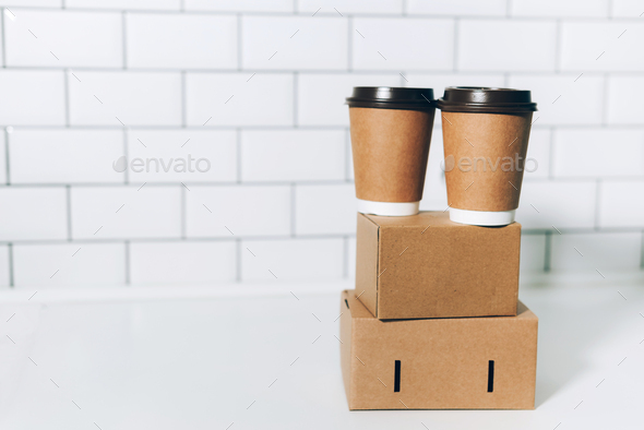 Craft paper cups with coffee to go and food box, lunch on tabletop over white kitchen. Banner, copy - Stock Photo - Images