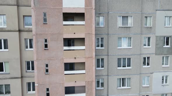 An Industrial Climber Suspended on Ropes and Paints the Wall of a Building with a Roller