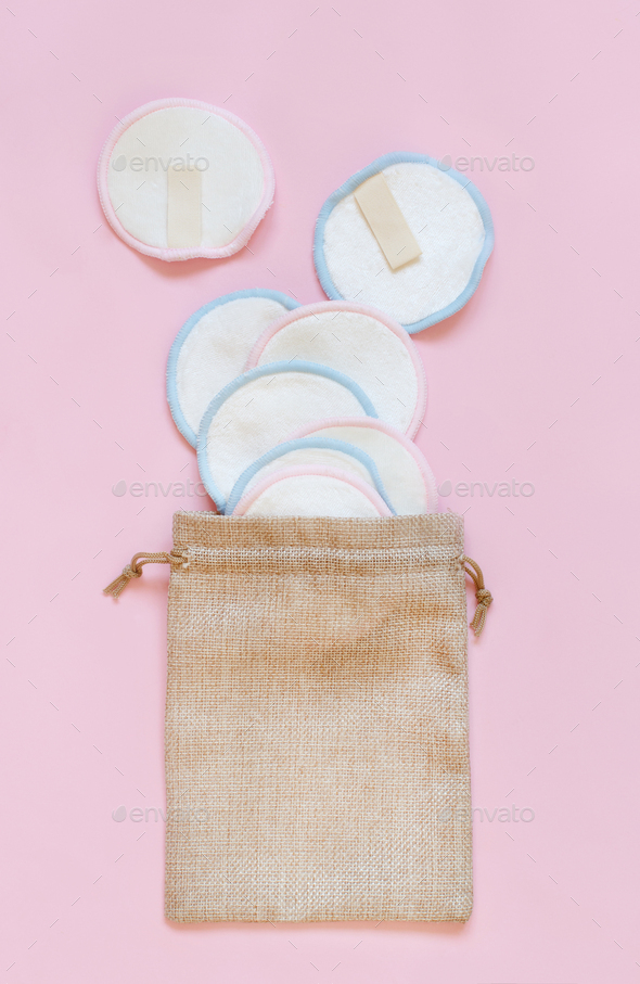 Eco friendly reusable make-up remover pads in a bag on pink background