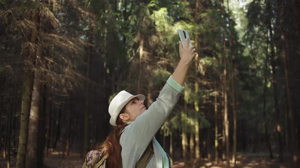 Traveler Woman Trying To Catch a Cell Signal on the Phone in the Forest, No Signal on the Phone alt
