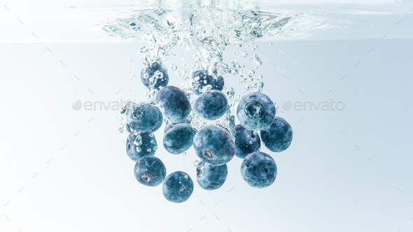 Bunch of blueberries splashing into water surface and sinking. Isolated on white background, splash - Stock Photo - Images