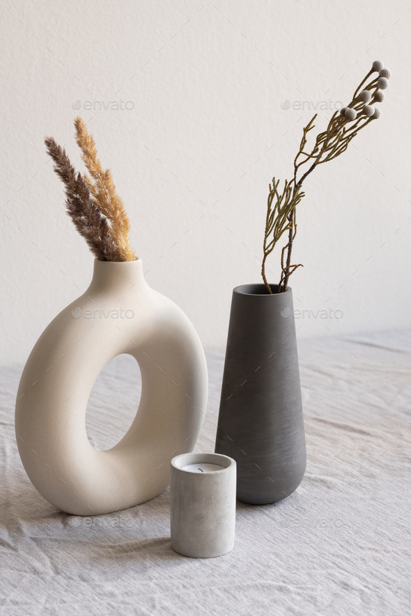 Two ceramic handmade vases with dried wildflowers and spikes and aromatic candle
