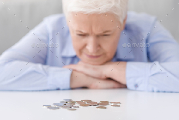 Elderly Poverty. Depressed senior woman looking at last coins lying at table - Stock Photo - Images