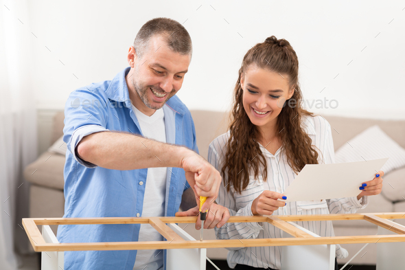 Cheerful Spouses Assembling Furniture Installing Cabinet Furnishing Home Sitting Indoor - Stock Photo - Images