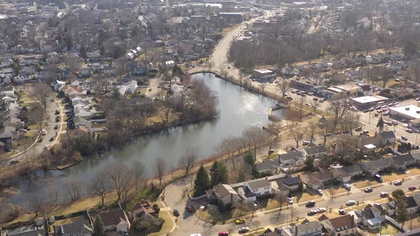 An aerial shot of a pond in a suburban neighborhood on Long Island, NY.  The camera dolly out, pan l alt