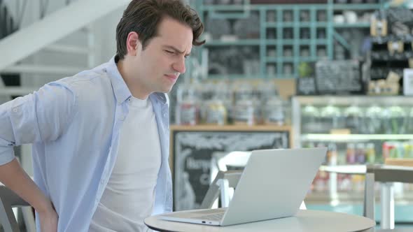 Young Man with Laptop Having Back Pain alt