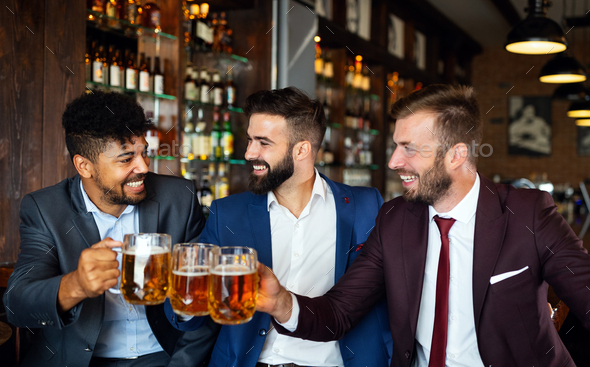 Handsome businessmen are drinking beer, talking and smiling while ...