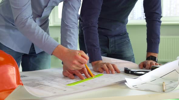 Two Architects Make Marks on the Plans of the Building
