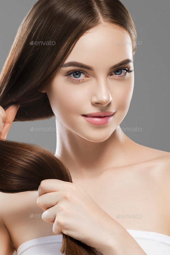 Smooth long brunette hair woman healthy strong with healthy clean skin female. On gray. Studio shot