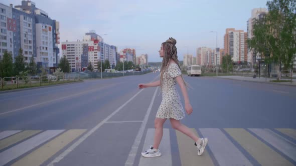 A Girl with Dreadlocks Walking Down a Road