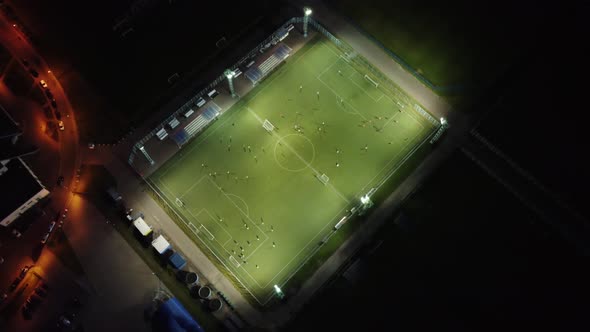 Football players train in the evening under artificial lighting. alt