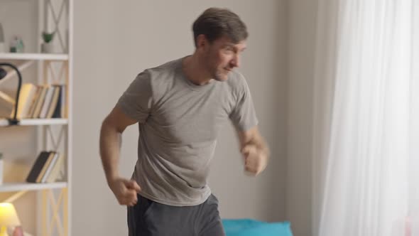 Concentrated Caucasian Man Boxing Shadow at Home in the Morning alt