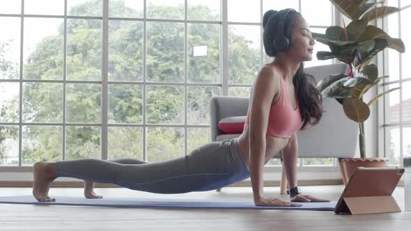 Beautiful yoga Asian woman practice in a training workout in the living room at home.