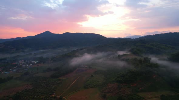 Aerial view from a drone over a misty landscape that covers the farmland alt