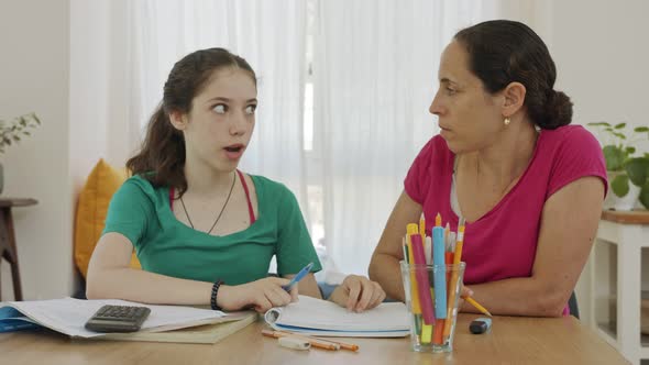 Mother helping her teenage daughter prepare homework alt