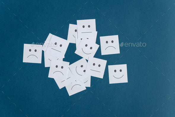 Many white post it papers with smiling sad and neutral faces on them