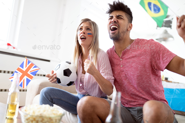 Young couple sport fans watching match on television at home