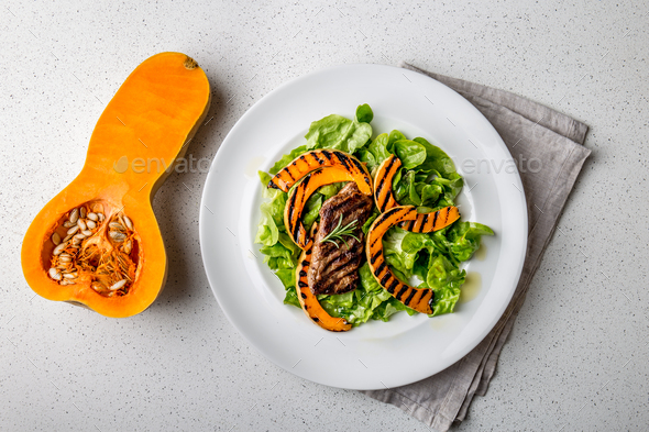 Grilled pumpkin and lettuce salad on white background.