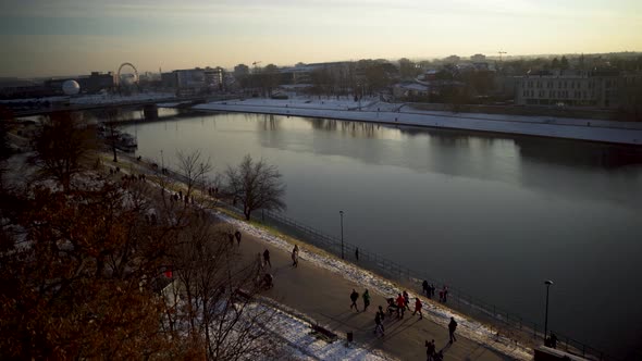 Aerial drone shot of vistula river and people taking a walk over weekend in Krakow city of Poland alt