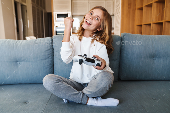 Photo of excited girl making winner gesture and playing video game