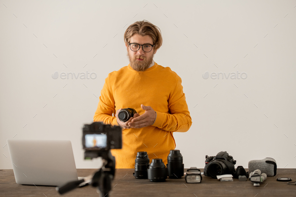 Bearded photographer showing component parts of new model of photocamera