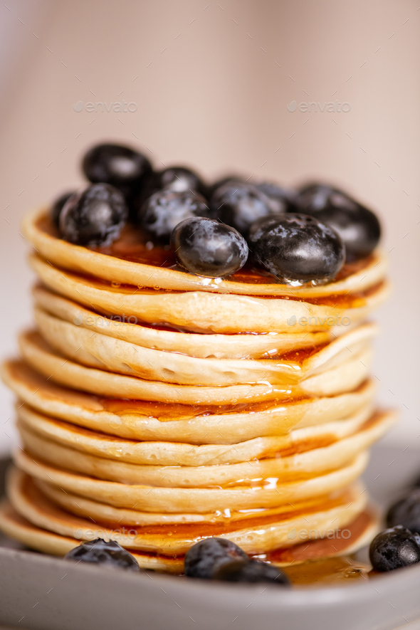 Stack of homemade appetizing crepes with fresh honey and blackberries