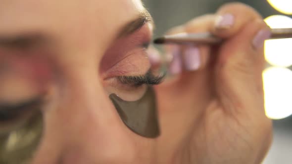 Makeup Artist Applying Eye Shadow to Model's Eye alt
