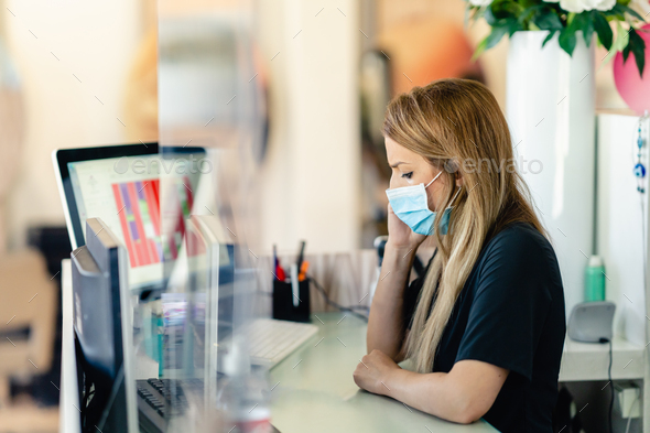 Female hairdresser answering the phone to give her clients an appointment, wearing a protective mask - Stock Photo - Images