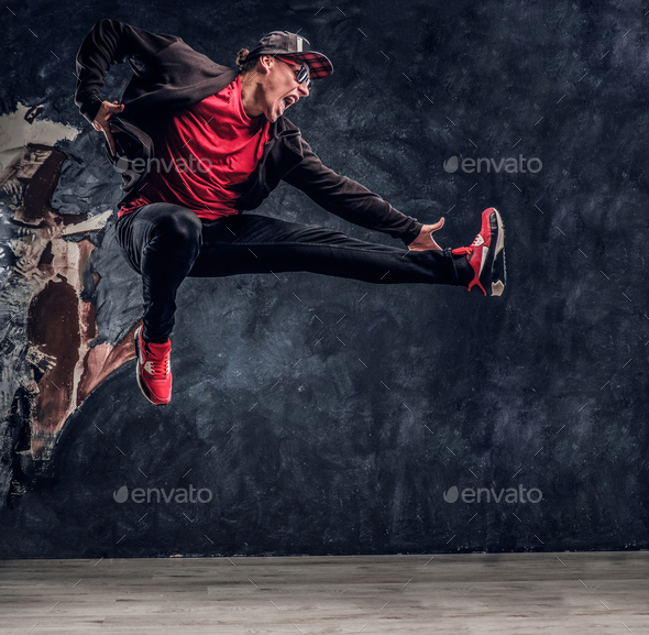 Emotional stylish dressed guy performing break dance jumping. - Stock Photo - Images