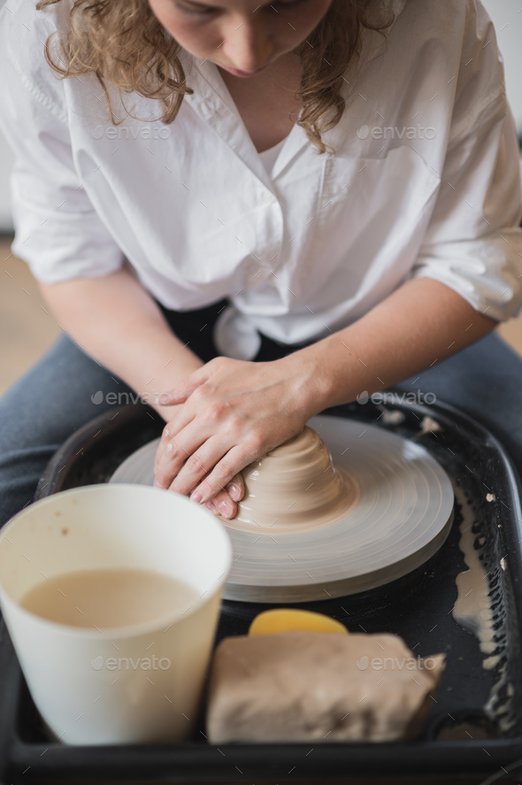 Girl makes pottery from clay. She making ceramic products from white