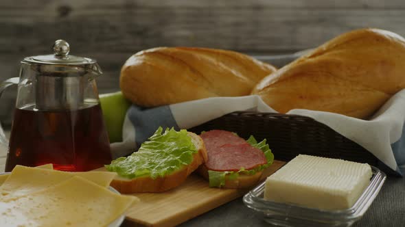 Appetizing Sandwich Is Prepared on a Cutting Board. Salad, Sausage and Cheese Are Cut Into a